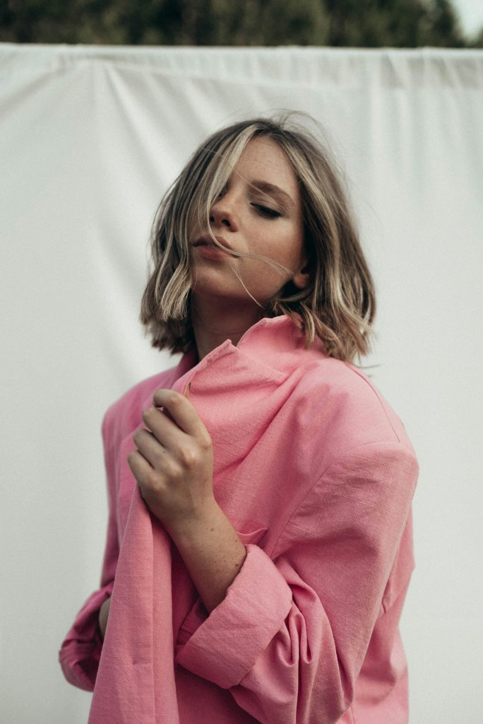 up-close photo of a woman with a pink button-up shirt