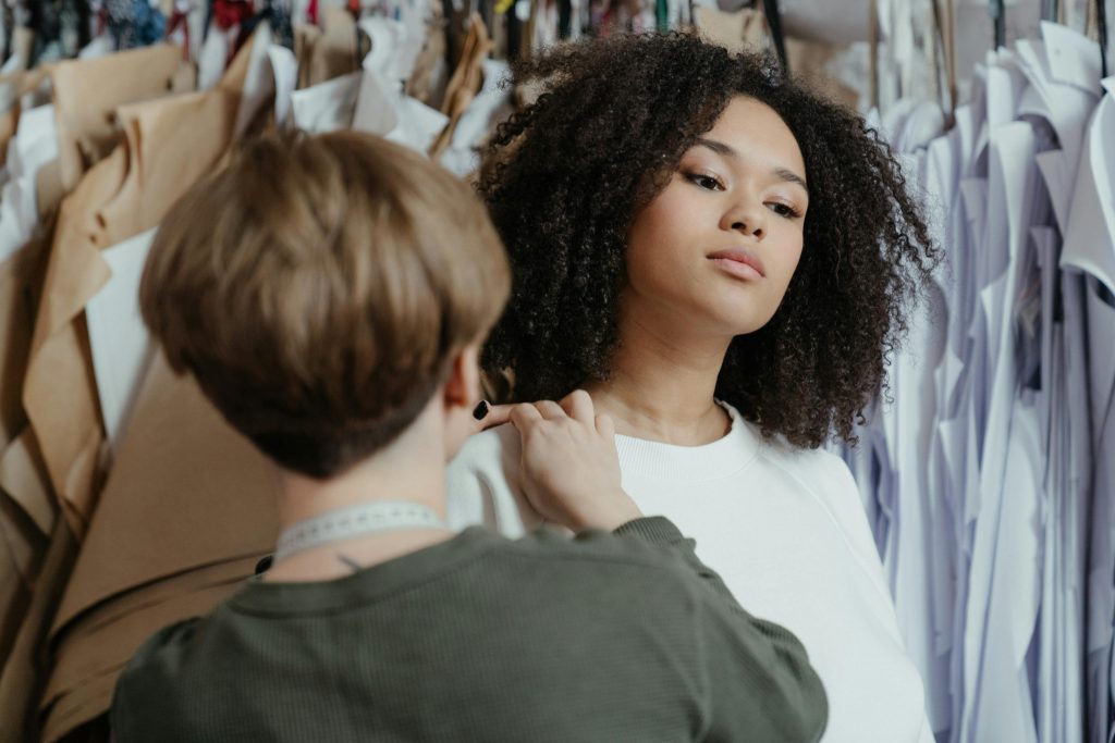 up-close photo of a model in fitting and a designer measuring the models shoulder