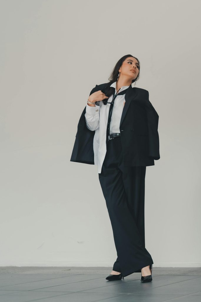 photo of a woman wearing black suit pants, heels, tailored jacket and a tie